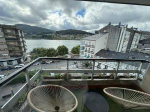 a balcony with two chairs and a view of a river at Piso en el centro de Viveiro in Viveiro