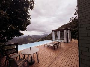 a deck with tables and chairs and a swimming pool at Sítio Turisfri in Nova Friburgo