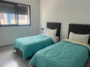 Dos camas una al lado de la otra en un dormitorio. en Appartement familial Soleil et Mer à 150m de la Plage de Mehdia, en Plage de Mehdia
