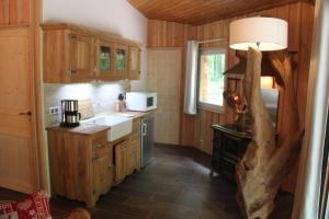 a kitchen with wooden cabinets and a table with a lamp at L'isba des bois, hors du temps in Janvry