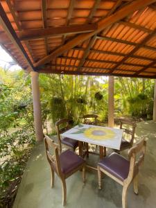 a table and chairs under a wooden roof at Casa em Guaramiranga, ao meio da Natureza! in Guaramiranga