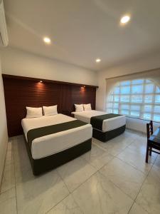 a bedroom with two beds and a large window at Hotel Colonial de Merida in Mérida
