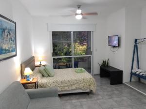 a bedroom with a bed and a couch and a window at Monoambiente Estela in San Pedro