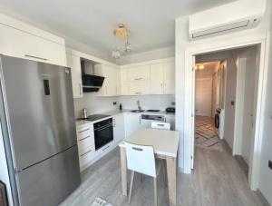 a kitchen with white cabinets and a table and a refrigerator at Vista Marina Çeşme in Çeşme