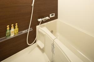 eine weiße Badewanne mit Dusche im Badezimmer in der Unterkunft Guest House Shine Bright - Vacation STAY 19290 in Fukuoka + 16 Fotos