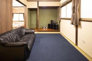 a leather couch in a living room with a blue carpet at Guest House Shine Bright - Vacation STAY 19289 in Fukuoka