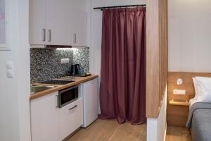 una piccola cucina con lavandino e tenda rossa di Enalis Studios & Apartments a Karfás