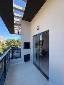 a balcony of a house with glass doors and a table at Residencial Brisa do Mar in Bombinhas