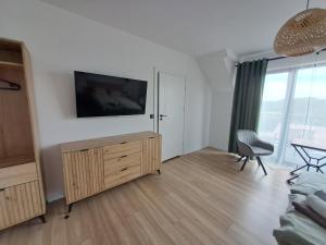 a living room with a flat screen tv on a wall at Nad Zatoką pokoje z widokiem na jezioro in Ryn