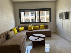 Una sala de estar con un sofá y un televisor. en Costa house, en Bouznika