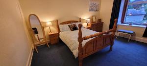 a bedroom with a wooden bed and a mirror at Pitlochry North Wing Apartment - very central in Pitlochry