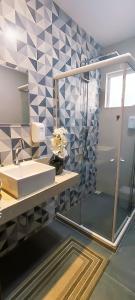 a bathroom with a sink and a shower with a mirror at Marbella Suíte, vista mar, piscina e churrasqueira in Arraial do Cabo