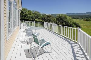 a deck with a table and chairs on a house at Weeks Hill: 5 br, fireplace, a/c, deck, views! in Stowe