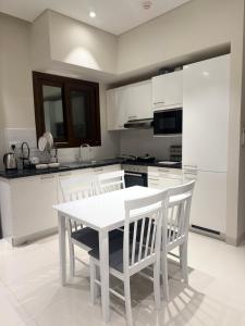 a white kitchen with a white table and chairs at صلالة هوانا in Ma‘mūrah