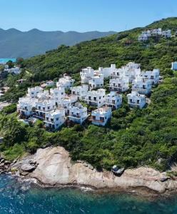 a group of white houses on a hill next to the water at Marbella Suíte, vista mar, piscina e churrasqueira in Arraial do Cabo