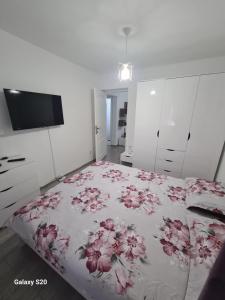 - une chambre avec un lit orné de fleurs roses dans l'établissement Apartament Central Slanic-Moldova, à Slănic-Moldova