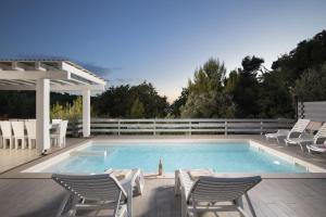 a swimming pool with chairs and a white fence at 8-bedroom Villa Bianca with Sea View and Pool Table in Premantura