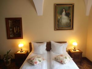 two beds in a room with two lamps and a painting at Gothic House in Sibiu