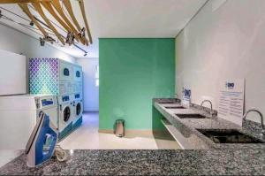 a kitchen with a washing machine and a green wall at Ap16 - Com 2 quartos, na rua do metrô Brás in São Paulo