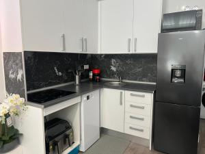 a kitchen with white cabinets and a black refrigerator at Villa potasa 19 in Madrid +15 photos