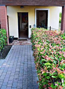 a house with a hedge of pink flowers in front of it at Claniland in Castelnuovo del Garda