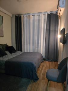 a bedroom with a bed and a chair and a window at Apartment Bombonjera in Užice +4 photos