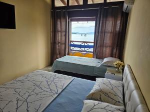 two beds in a room with a window at Aspidiske in Governador Celso Ramos
