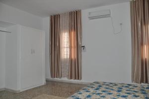 a bedroom with a bed and a window with curtains at Appartement neuf et meublé in Houmt Souk