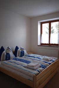 1 dormitorio con 1 cama grande con sábanas azules y ventana en HORSKÁ CHATA SOBÍK en Dolní Morava