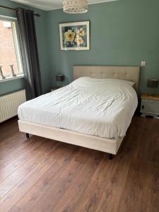 Schlafzimmer mit einem weißen Bett und Holzboden in der Unterkunft Vakantiehuisje Wekerom in Wekerom