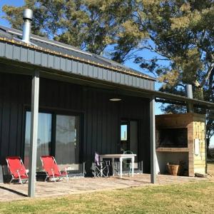 a black house with two red chairs and a table at Casa de Campo Galpon San Antonio de Areco in San Antonio de Areco +19 photos