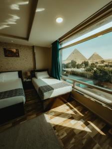 a room with two beds and a view of the pyramids at Turquoise Pyramids & Grand Egyptian museum view Hotel in Cairo +77 photos