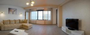 un salon avec un canapé et une télévision à écran plat dans l'établissement Vila Sophia 2 Mamaia, apartament cu piscina si vedere catre lac, à Mamaia