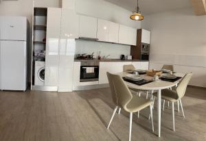 une cuisine avec une table, des chaises et un réfrigérateur dans l'établissement Vila Sophia 2 Mamaia, apartament cu piscina si vedere catre lac, à Mamaia