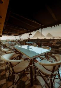 a group of tables and chairs with pyramids in the background at Turquoise Pyramids & Grand Egyptian museum view Hotel in Cairo