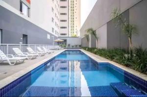 a swimming pool with chairs and a building at Ap16 - Com 2 quartos, na rua do metrô Brás in São Paulo