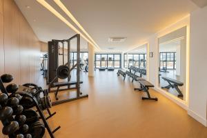 un gimnasio con una fila de cintas de correr y máquinas en The Bridge by Xtay -Estúdios em Floripa com Piscina no Rooftop e Academia Completa, e fácil acesso as Praias Populares, en Florianópolis