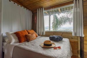 1 dormitorio con 1 cama con sombrero y gafas en Refúgio Panorâmico na Casa de Vidro, en Imbituba