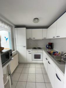 a kitchen with white cabinets and a sink at Badehausallee 20 Bungalow in Cuxhaven +11 photos
