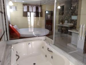 a white bath tub in a bathroom with a shower at Hotel e Motel Rarus in Igaratinga +5 photos