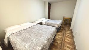 two beds in a small room with wooden floors at WIFI Rápido A 20 min del Aeropuerto de Lima in Lima