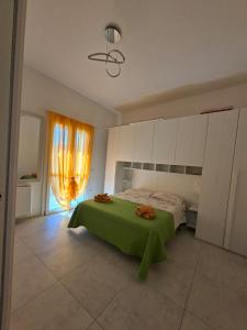 een slaapkamer met een bed met een groene deken erop bij APPARTAMENTO Dal Duca Enrico in Castelsardo +4 foto's