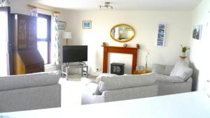 a living room with couches and a flat screen tv at 9 Rock Towers in Looe