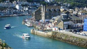 a group of people walking on a pier next to a river at 9 Rock Towers in Looe