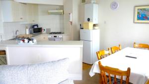 a small kitchen with a table and a white refrigerator at 9 Rock Towers in Looe +6 photos
