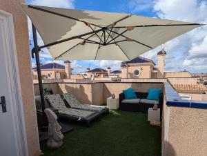 a patio with a couch and an umbrella on a balcony at Casa Kave Euro Roda-Los Alcazares in Los Alcázares