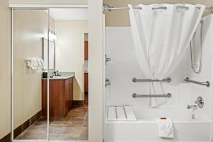a bathroom with a shower and a tub and a sink at Ledgestone Suites Hotel Elko in Elko