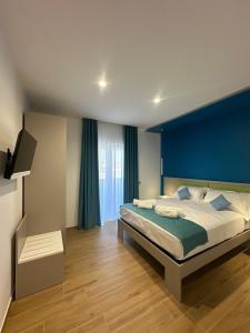 Un dormitorio con una cama grande con una pared azul. en Neas Resort, en Castel Volturno