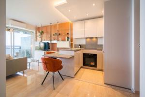 a kitchen with white cabinets and a table and chairs at La mirandole bleue, votre escapade face à la mer in Vallauris