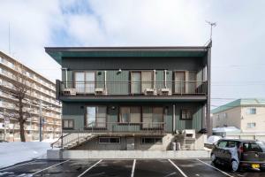 ein grünes Gebäude mit einem Auto auf einem Parkplatz in der Unterkunft ETRANA - Vacation STAY 19510 in Sapporo